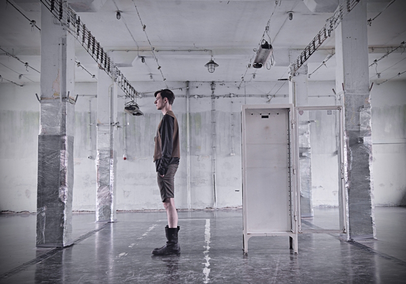 Side view of a model in a tobacco top and shorts in a bare industrial hall