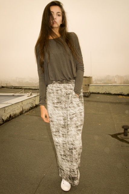 Model on a rooftop in a grey top and printed floor length skirt