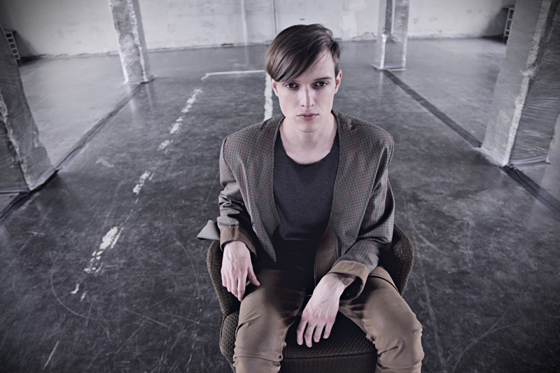 Model seated in a checked jacket worn over a charcoal top